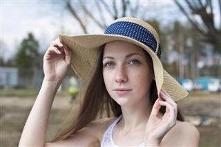 Freckled happy girl holding hat and looking at camera