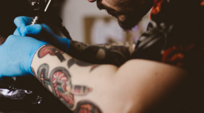 Person getting a tattoo by a tattooed man