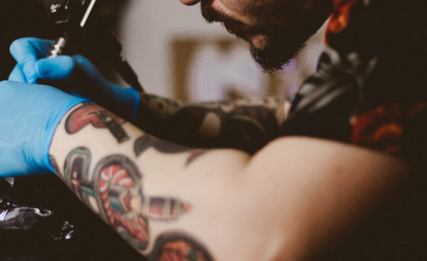 Person getting a tattoo by a tattooed man