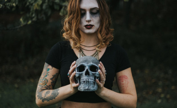 Girl with tattoos holding a gothic skull