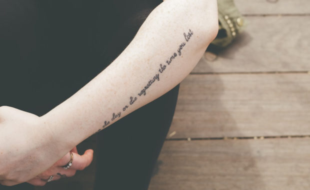 A person with tattoo writing going up their forearm